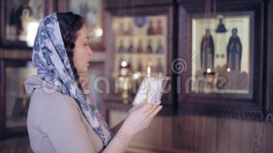 俄罗斯东正教教堂里戴着红头发、头戴着围巾的妇女点燃了<strong>蜡烛</strong>，在前面<strong>祈祷</strong>