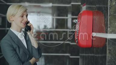 在<strong>酒店</strong>大堂的<strong>接待处</strong>，一位开朗的女商人与带有线红电话的工作人员交谈。 商务、旅行和