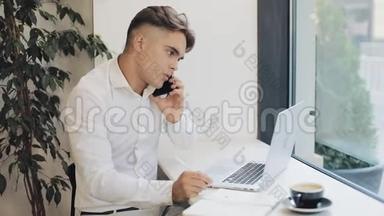 中镜头集中年轻商人在咖啡休息时打电话时在笔记本上记笔记
