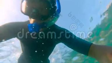 一个年轻人浮潜和潜水潜入海里的慢动作镜头。 一件衬衫袖子上的U.F50-表明