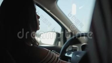 年轻女子在城里开车。 一位坐在车里的美女的肖像，<strong>望</strong>着<strong>窗外</strong>，微笑着
