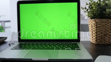 在客厅的办公桌上展示绿色彩色钥匙屏幕的笔记本电脑。 在背景舒适的客厅里。 多利鞋