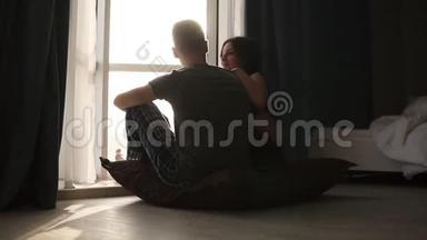 一对浪漫的夫妇穿着睡衣坐在地板上。 美丽的年轻白种人女人和男人坐在