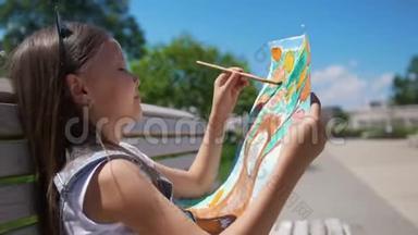 夏<strong>日儿童</strong>画家用画笔和水彩坐在长凳上画画