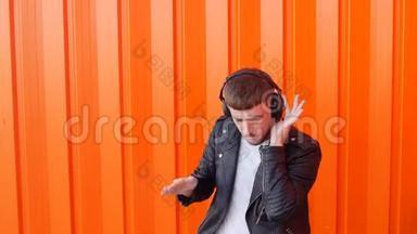 年轻的白种人戴着音乐耳机，听着橙色背景的音乐和舞蹈，Prance，慢动作，耳机
