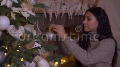 一个年轻的女孩装饰一棵圣诞树，有一个美丽的球，心情很好。 <strong>高清高清</strong>
