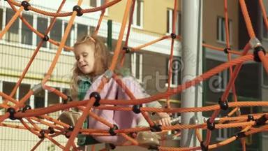 一个孩子在户外操场上爬上一根绳子的水平杆