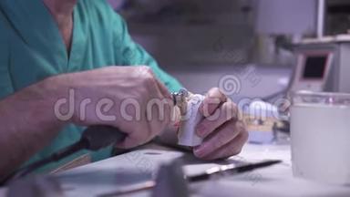 一名男子的手在工作中的牙科假肢磨床