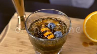 在岩石玻璃上的酒精鸡尾酒，<strong>桌面上</strong>有橙色、冰和蓝莓。