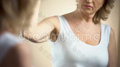 60岁的悲伤女人在镜子里抚摸她松弛的皮肤，自卑