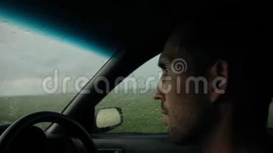 年轻的胡子男人开车。在雨中开车。
