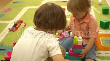 快乐的学龄前幼儿在室内操场上玩多种颜色的积木。 幼儿园教育