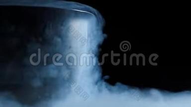 来自金属碗的液氮蒸汽沿着平坦的黑色表面爬行。地上浓烟和蒸汽。美丽的