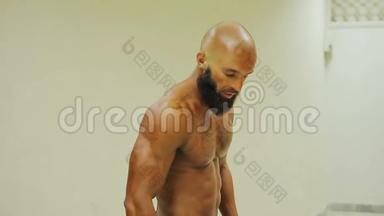 深褐色健美运动员展示强壮的身体，在体育俱乐部展示三头肌