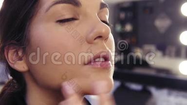 化妆师`在美容工作室里用<strong>遮瑕</strong>膏在一个漂亮迷人的女孩的脸上`T区的过程。
