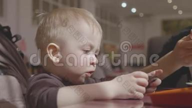 可爱的小男孩坐在咖啡馆里，和父母通<strong>电话</strong>看<strong>动画</strong>片。