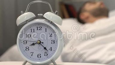 白色闹钟与睡眠男站在床边，健康睡眠，特写