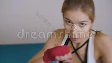 年轻女子用手裹着红色的<strong>拳击</strong>磁带<strong>拳击</strong>。 看看相机。 漂亮的女<strong>拳击</strong>手训练