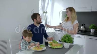 吃饭的时候，年轻的一家人在家里吃晚饭时互相欢笑和拥抱