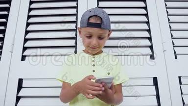 一个满意的可爱的小男孩在智能手机上玩游戏的肖像隔离在白色背景上。 儿童在线游戏