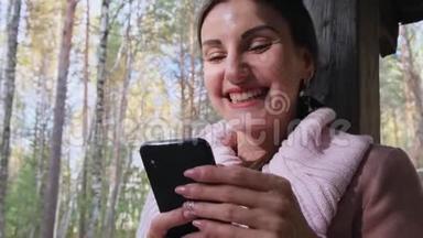 秋天森林里的一个开朗的女人在电话上交谈，在智能手<strong>机上</strong>发送信息，在手<strong>机上</strong>读一些东西