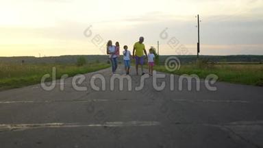 幸福的家庭在农村沿着这条路走。 有三个孩子的成熟父母在大自然中玩得很开心。 家庭、父母身份