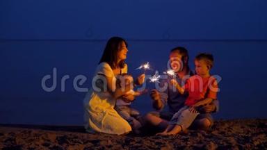 快乐的年轻家庭在黄昏的海滩上庆祝，<strong>孩子</strong>们和父母在<strong>唱歌</strong>，手捧烟花
