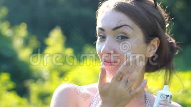 一位年轻的女士正在从阳光下涂上<strong>防晒</strong>霜。