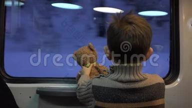 小孩子拿着玩具熊玩具看着窗外，在生活中纳闷，冬天的风景