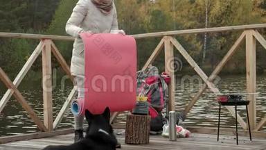 河岸附近桥上的一位女游客从背包里拿出东西，在她旁边铺上一块旅游地毯