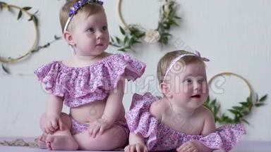 两个穿着粉色服装的女孩在墙的背景上摆着装饰的照片