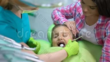 小女孩定期做牙齿检查，妈妈抱着女儿，镇静下来