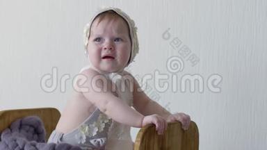 一个穿着头饰的小女孩坐在木箱里，在镜头上摆姿势拍照