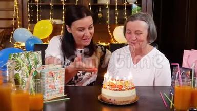 女儿和高年级妈妈在生日蛋糕或母亲节聚会上吹蜡烛
