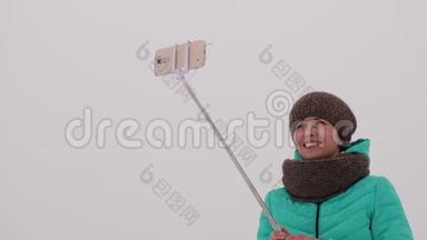 女孩在智能手机和自拍上拍照，在冬季公园-在圣诞节早上。 快乐的女孩走在雪地里