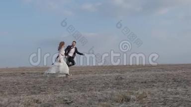 快乐的年轻夫妇<strong>牵着</strong>手穿过一片广阔的田野，在户外玩得很开心。 乡村。 男人和女人在奔跑