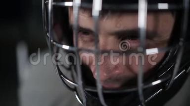 特写守门员曲棍球运动员戴着防护头盔看着镜头。 守门员的面部表情