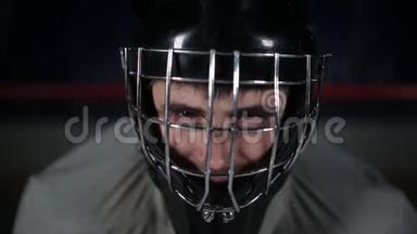 特写守门员曲棍球运动员戴着防护头盔看着镜头。 守门员的面部表情