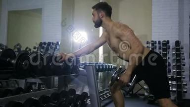 一个运动健将在健身房锻炼手臂肌肉，在镜子旁边的一个架子上锻炼一个哑铃