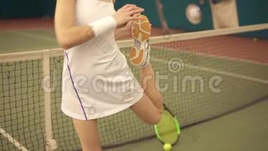 穿着白色运动服的女子网球运动员在开始比赛前伸展腿部肌肉