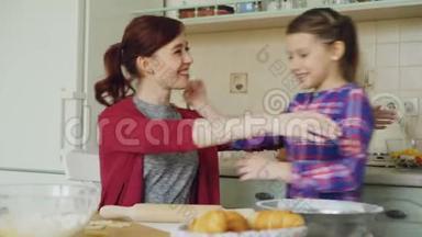 快乐的妈妈在厨房做饭，而可爱的女儿早上来拥抱妈妈。 家庭，食物，家