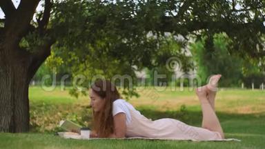 年轻女子躺在树下看书