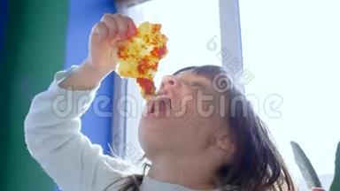 饥饿的蹒跚学步的孩子正在阳光明媚的披萨店里吃垃圾食品