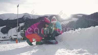 母亲帮助女儿在滑<strong>雪坡</strong>上正确地穿上滑雪板。