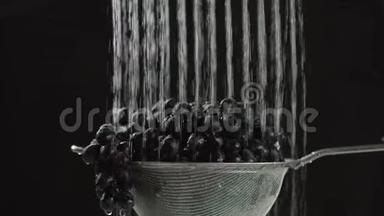 在<strong>视频</strong>中，我们看到葡萄在筛子中，水从顶部<strong>开始</strong>下降，相机从上到下移动，黑色背景。