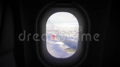 透过飞机的窗户观看蓝天和云彩。 带有飞机机翼的飞机窗口。