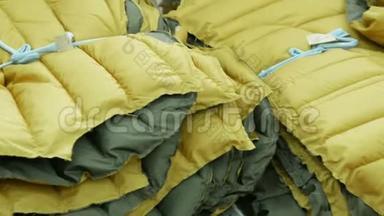 黄色的冬季夹克在服装厂的仓库里系在一起。 定制概念