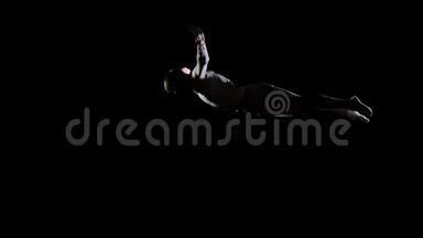 在蹦床上的黑色背景上跳跃体操运动员。 自由和飞行