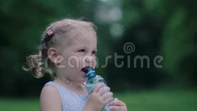喝水。小女孩在户外用瓶子喝水