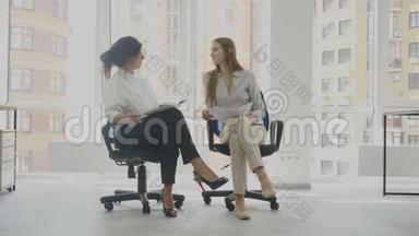 办公室工作人员，两名妇女坐在椅子上交谈，其中一名妇女讲述另一名妇女的工作